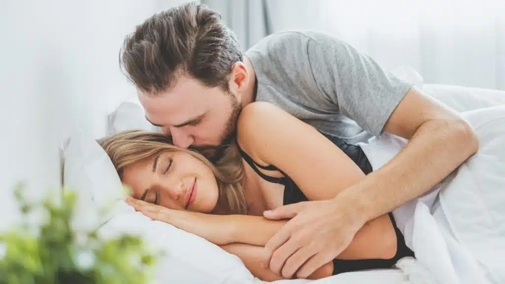 A man kissing his sleeping wife.