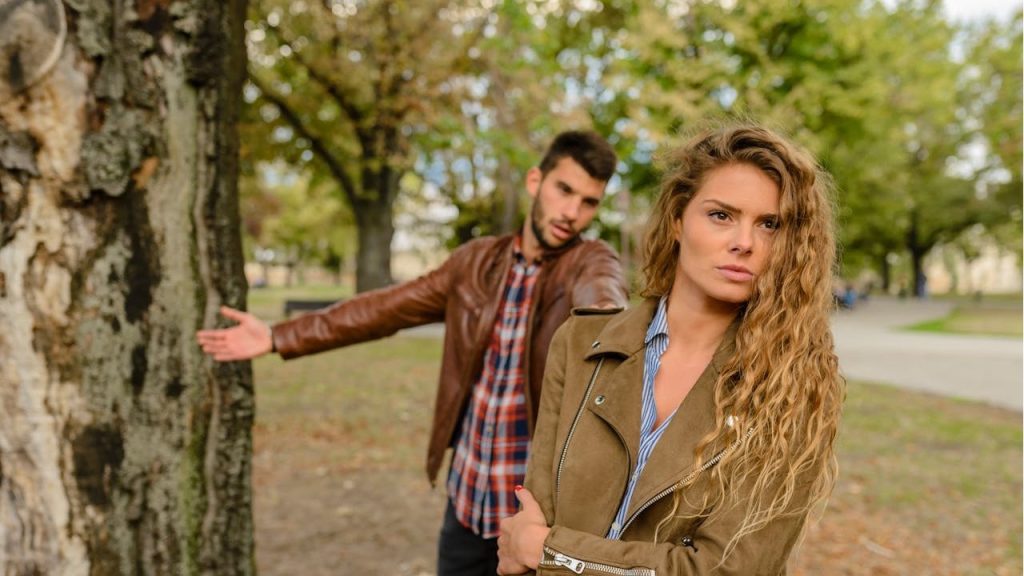 Woman with curly hair turning away from a man who is trying to talk to her.