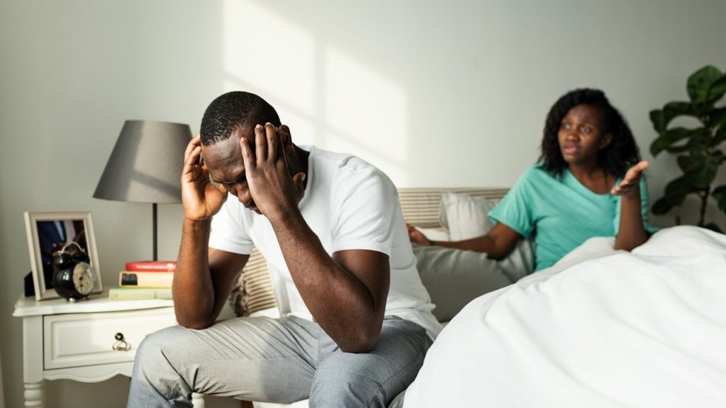 A woman nagging her husband, the distressed man touching his head with his hands.