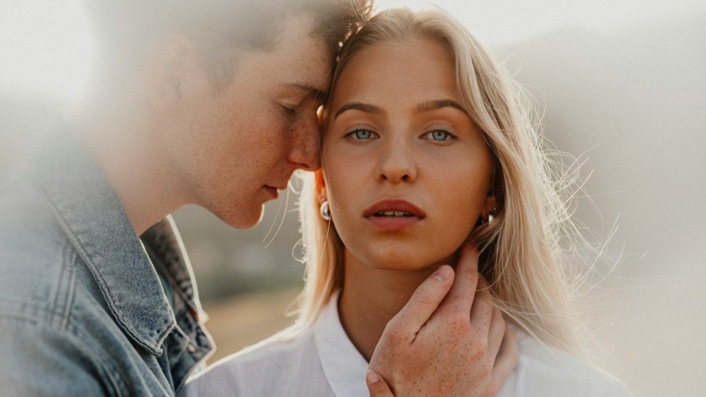 A man embracing his partner who is looking in the camera.