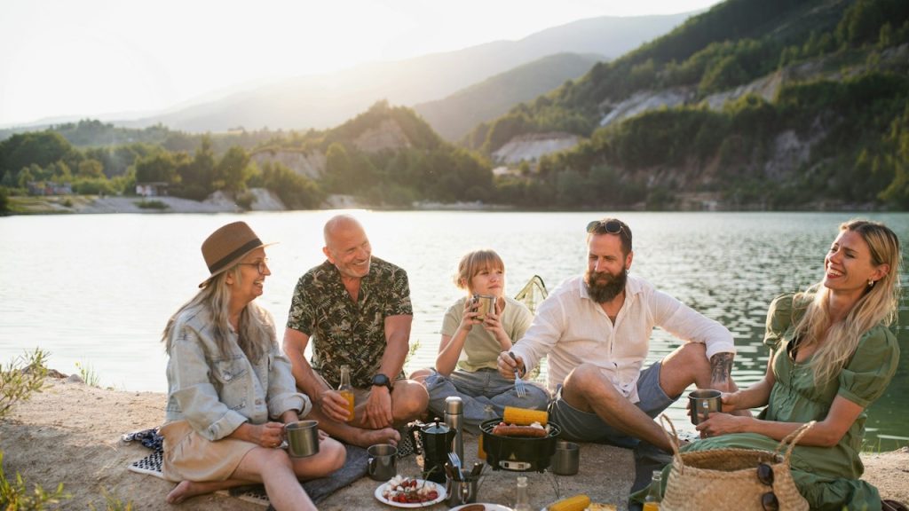 A happy multigenerational family on a summer holiday trip barbecue by the lake.