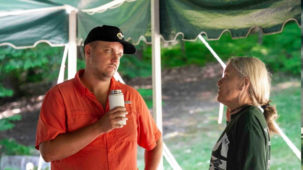A man and woman are talking under a tent.