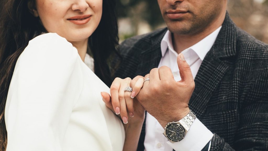 Newlywed couple holding pinky fingers.