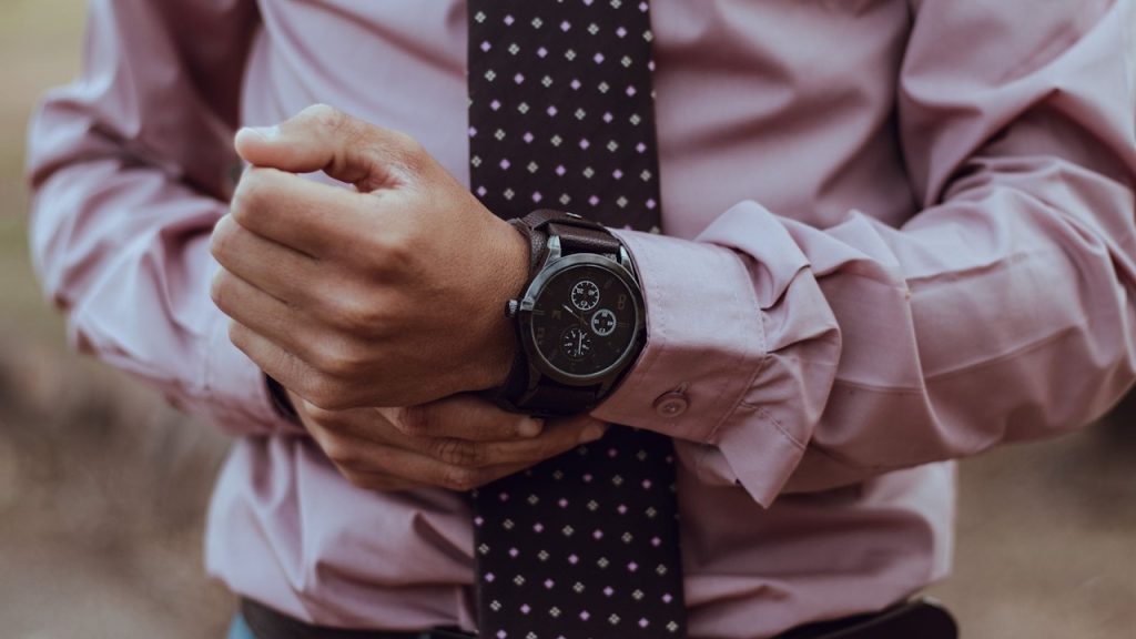A man in a pink shirt and necktie wearing a watch