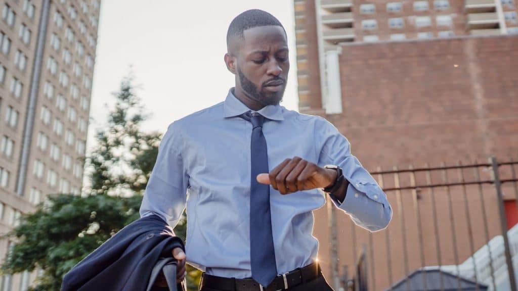 A man in a suit looking at a watch.