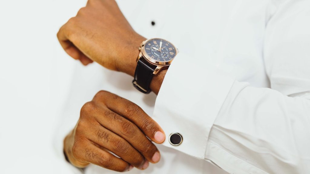 Close-up of an elegantly dressed man adjusting his wristwatch.