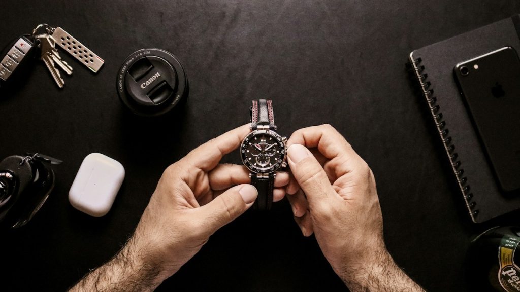 A person holding a silver-and-black-round-analog watch.