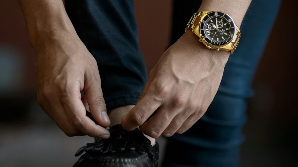 A man tying his shoelaces while inside a room during the daytime.