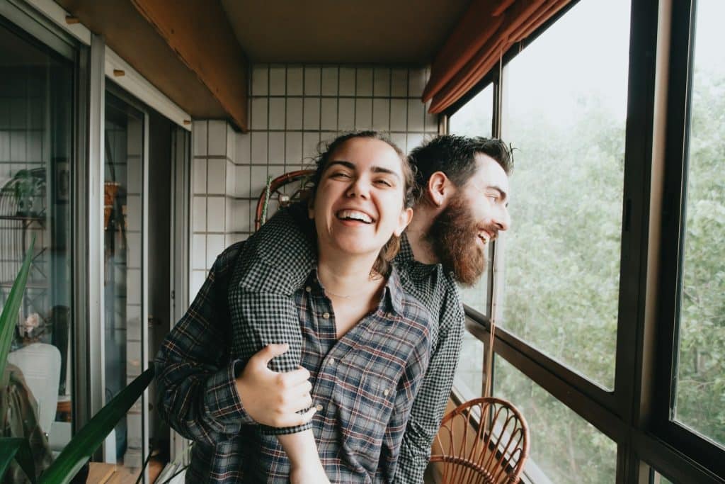 A man puts his arm on a woman’s shoulder, and they laugh together.