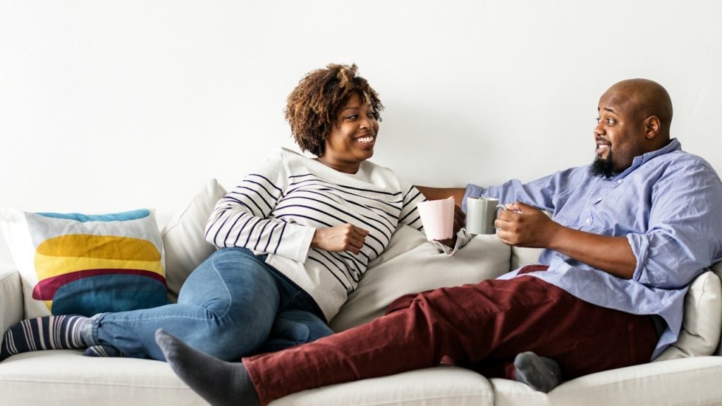 A happy couple relaxing and having coffee on a sofa.