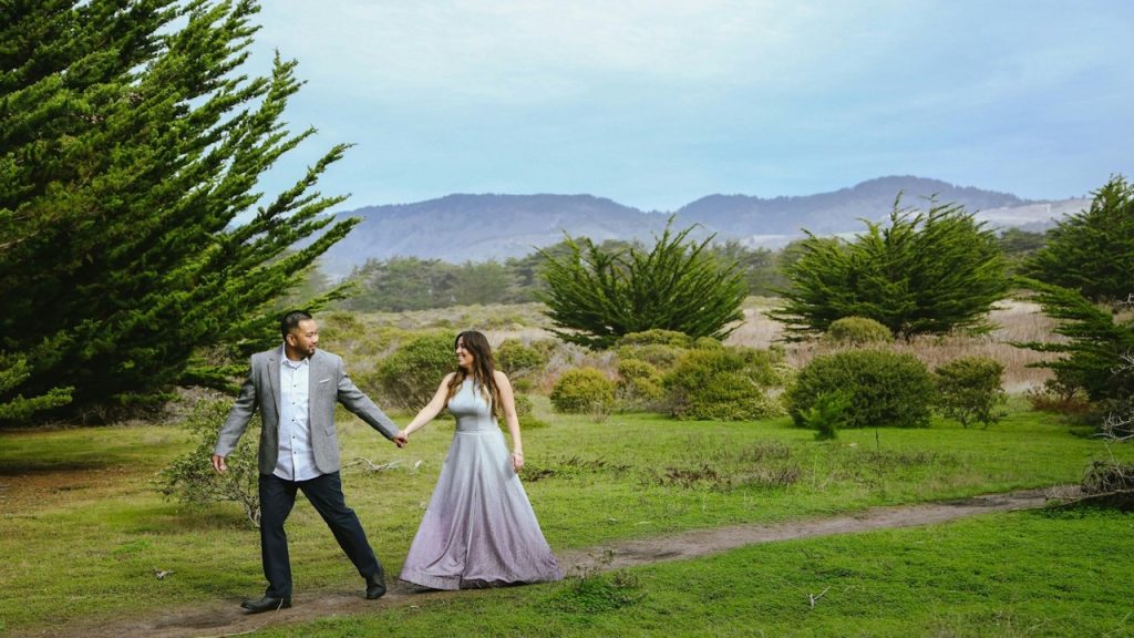 A man and a woman holding hands and walking through a field.