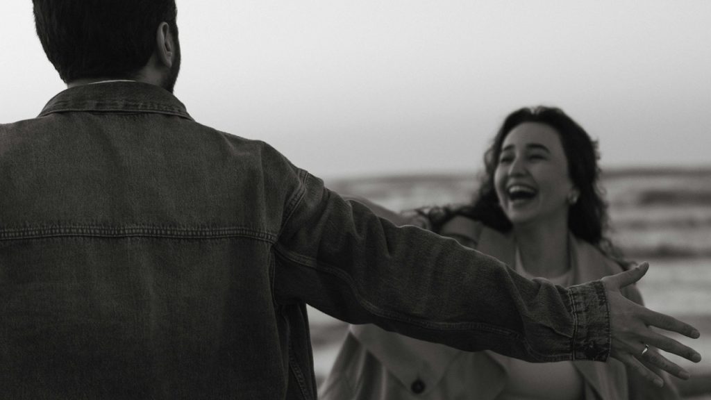 A couple embracing on a beach with joy.