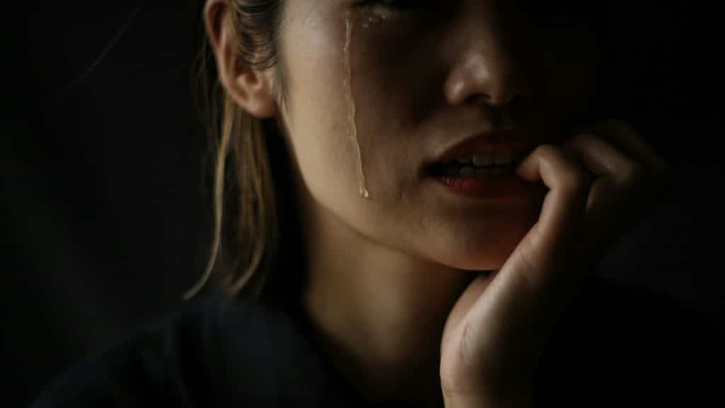A woman who bites her nails while shedding tears.