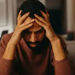 A depressed man holding his head with his hands.