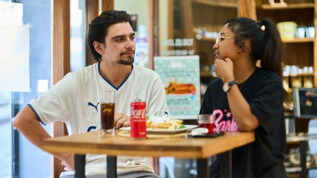 A couple chatting and eating at a cafe.