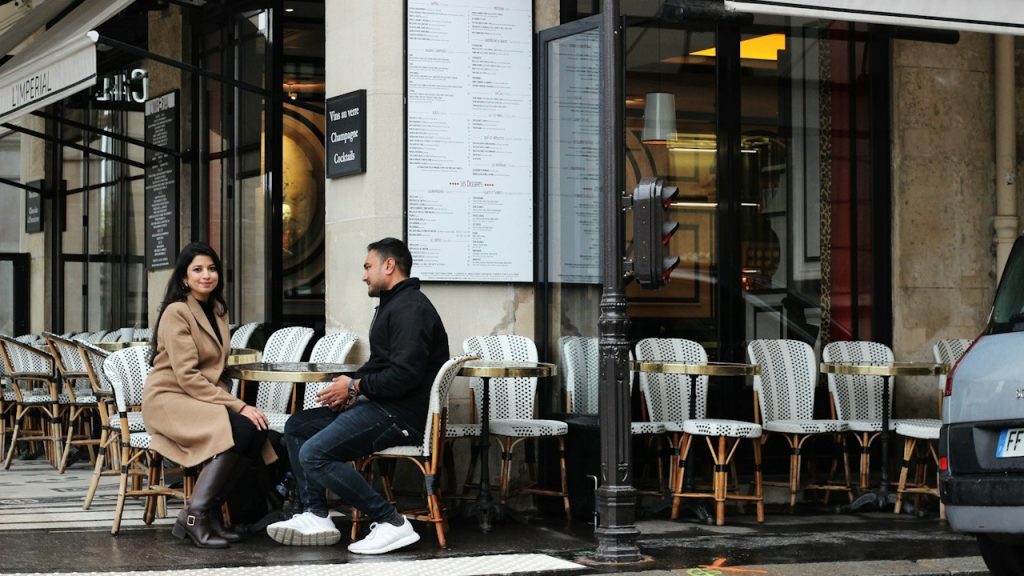 A man and woman sitting at an outdoor table set.