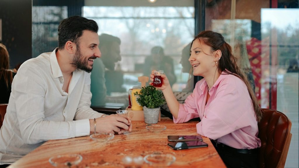 A man and a woman having coffee while sitting at a table.