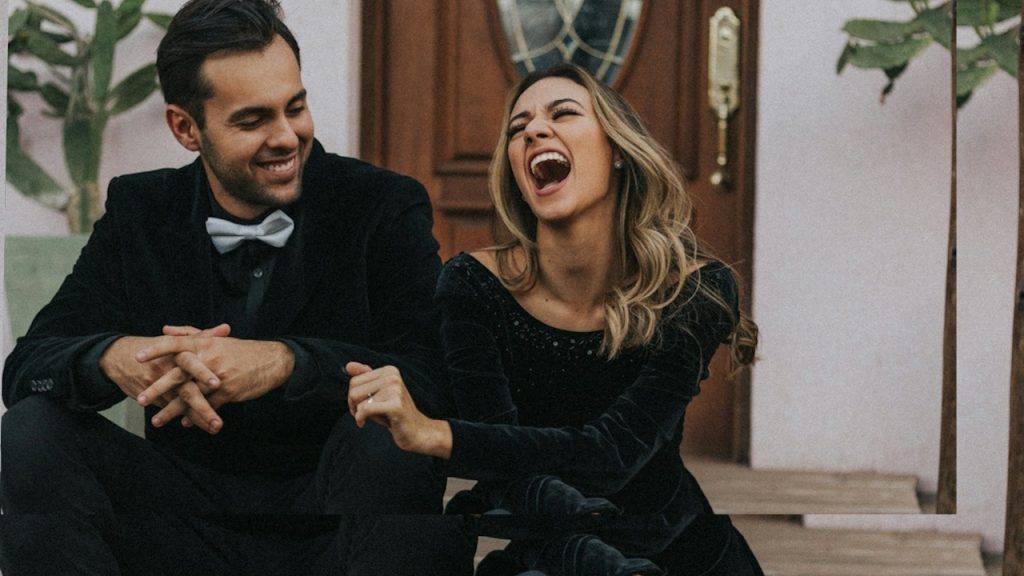 A couple wearing black dreses are sitting and laughing together.