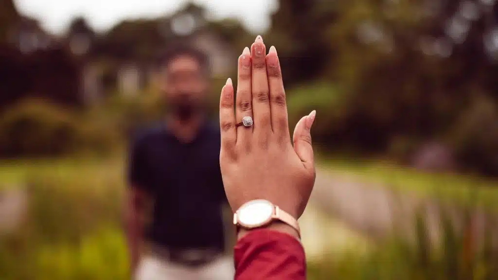 A woman’s hand and a man in the background.