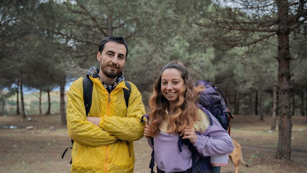 A man and a woman standing in a forest.