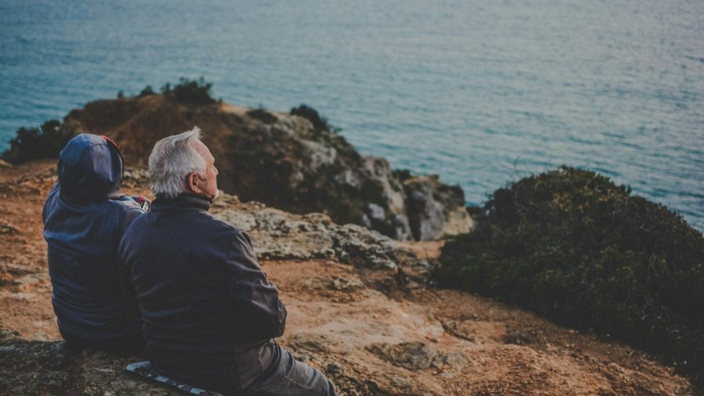 An older couple sitting by the sea.