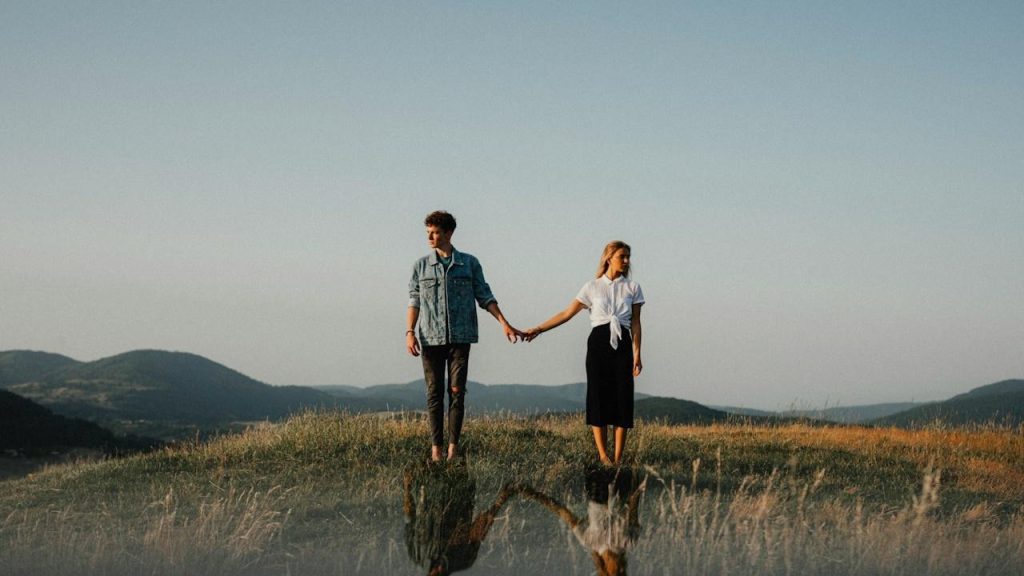 A young couple standing in nature holding hands but looking away.A young couple standing in nature holding hands but looking away.A young couple standing in nature holding hands but looking away.A young couple standing in nature holding hands but looking away.A young couple standing in nature holding hands but looking away.