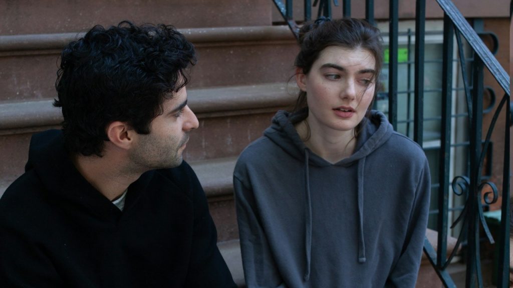A man and a woman talking while sitting on stairs.