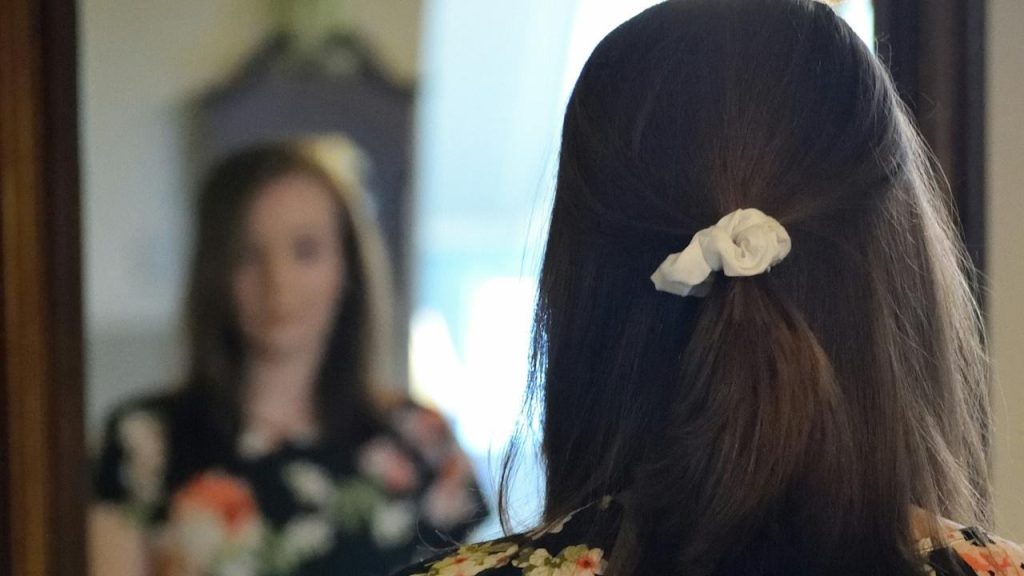 A woman looking at her reflection in the mirror.