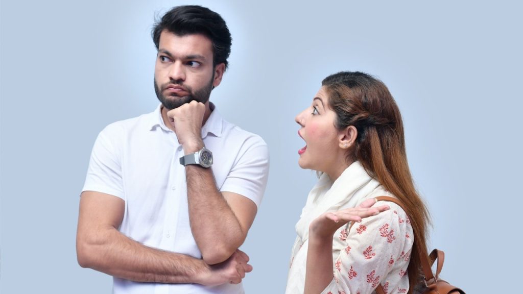 A woman shouting at a bearded man who’s looking to the side and holding his fist to his chin.