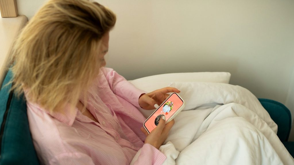 A woman holding a cellphone is using a dating app on it.