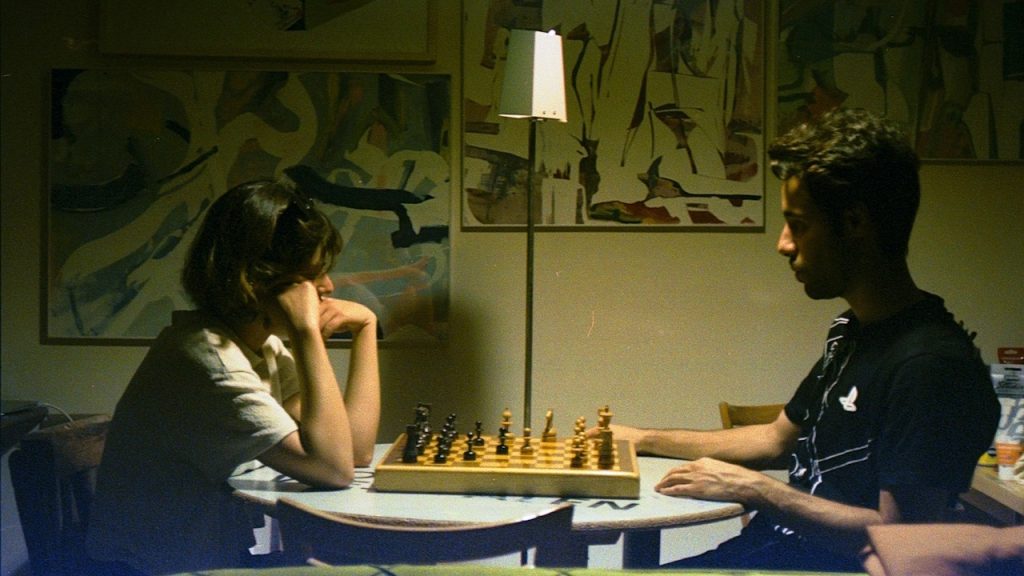 A couple plays chess together indoors.