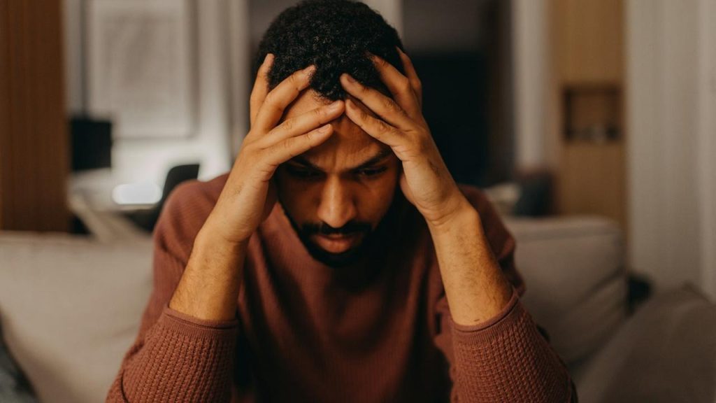 A depressed man holding his head with his hands.