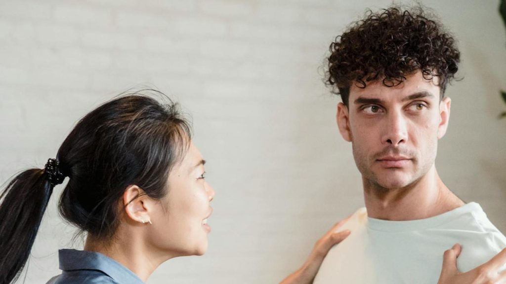 A woman talking to a man with curly hair.