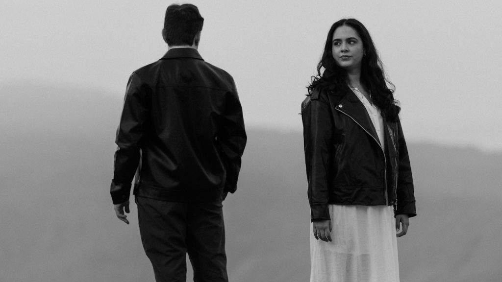 A couple standing with their backs to each other and looking in opposite directions.