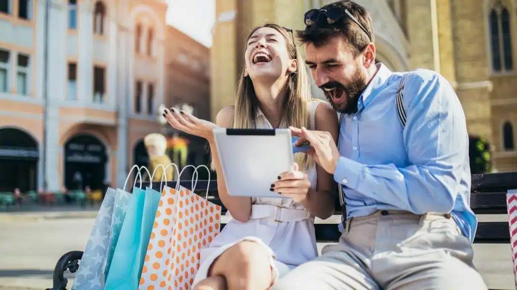 A young couple using a digital tablet for online shopping outdoors.