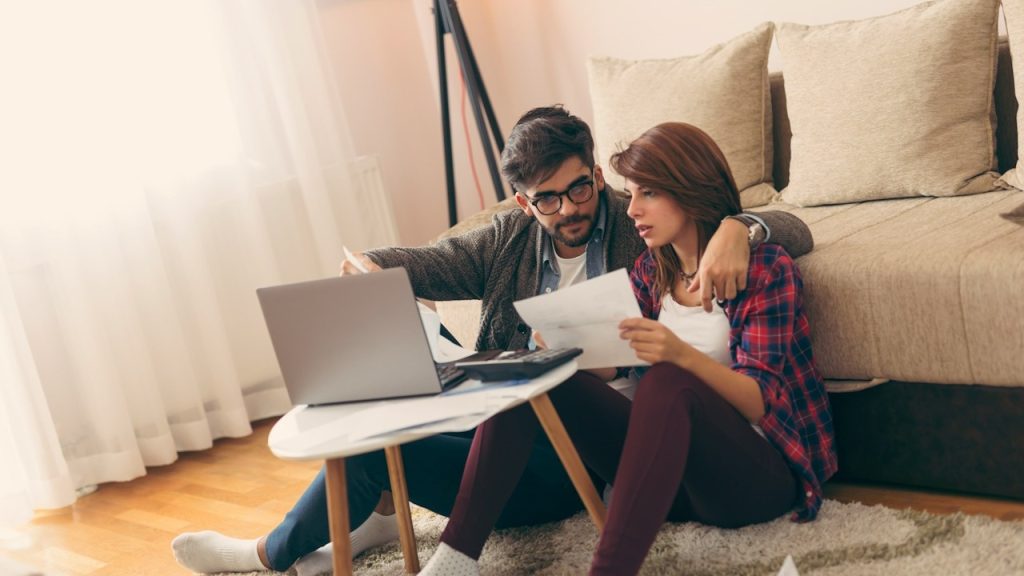 A young married couple doing their paperwork together, paying bills online.