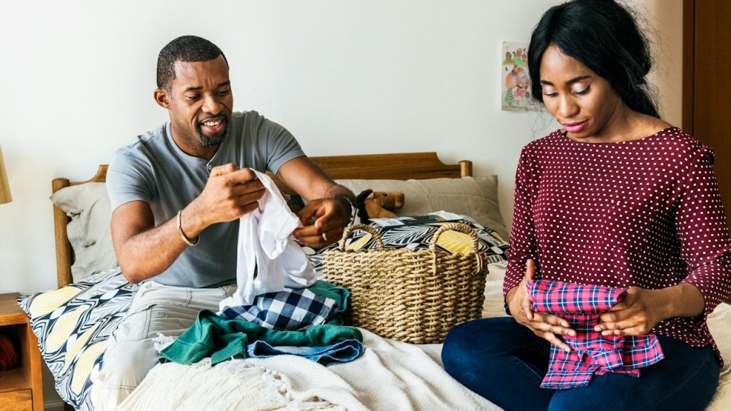 A Black couple folding clothes together.