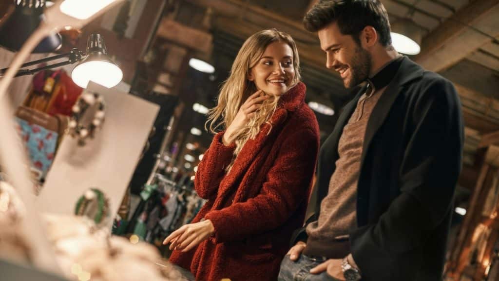 Happy young joyful couple choosing handmade imitation jewelry at a small street market.