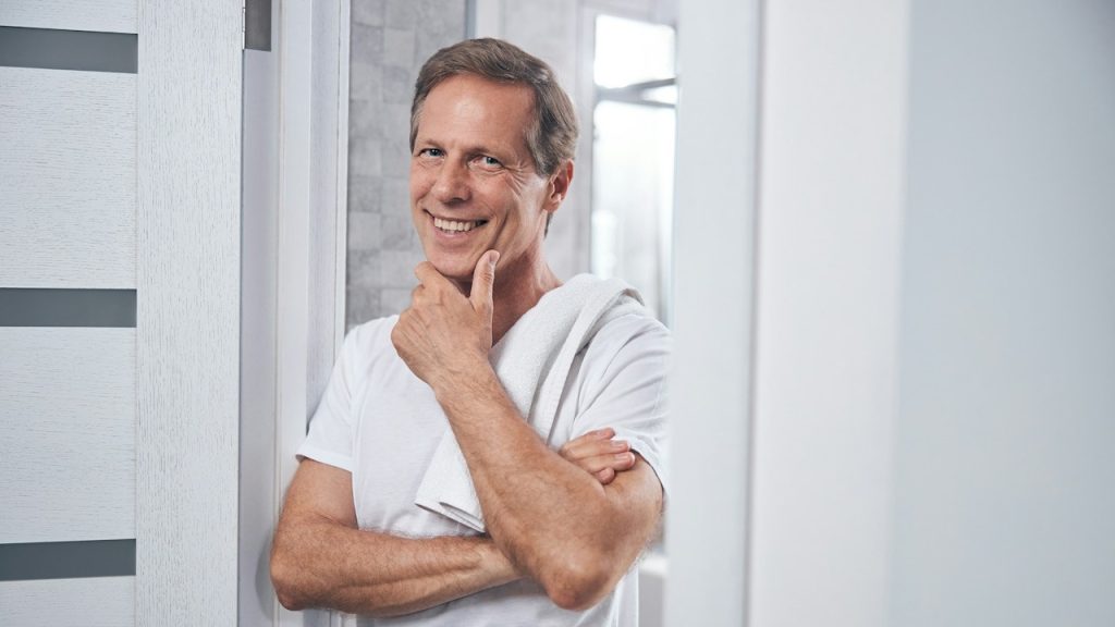 A happy man in a t-shirt propping his chin on his hand.