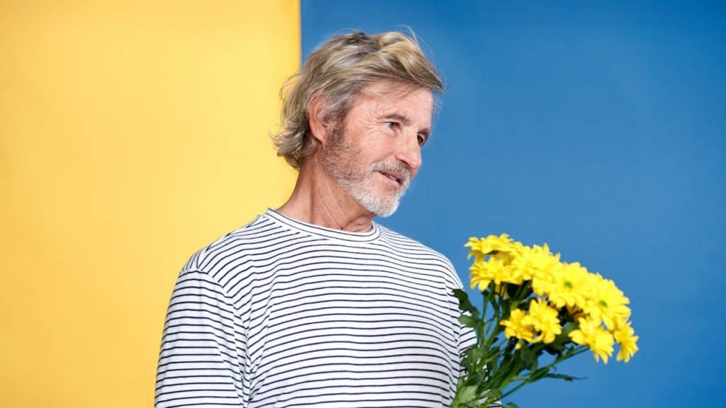 A man holding an assortment of yellow flowers.