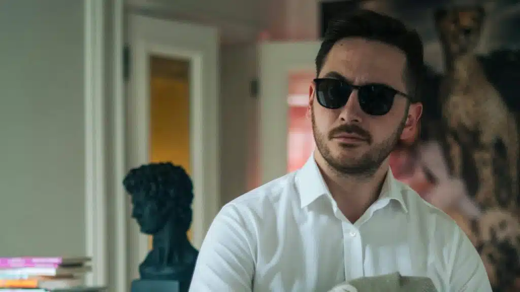 A confident bearded man in sunglasses in a museum.
