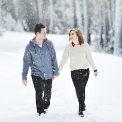 A couple walking on snow near trees during daytime.
