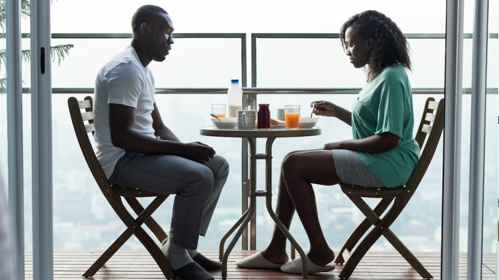 A couple having breakfast while sitting quietly at a table.