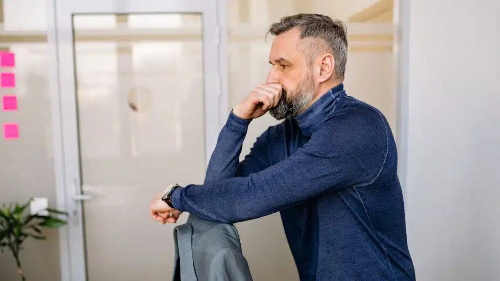 A man in a blue long-sleeved shirt standing near a doorway.