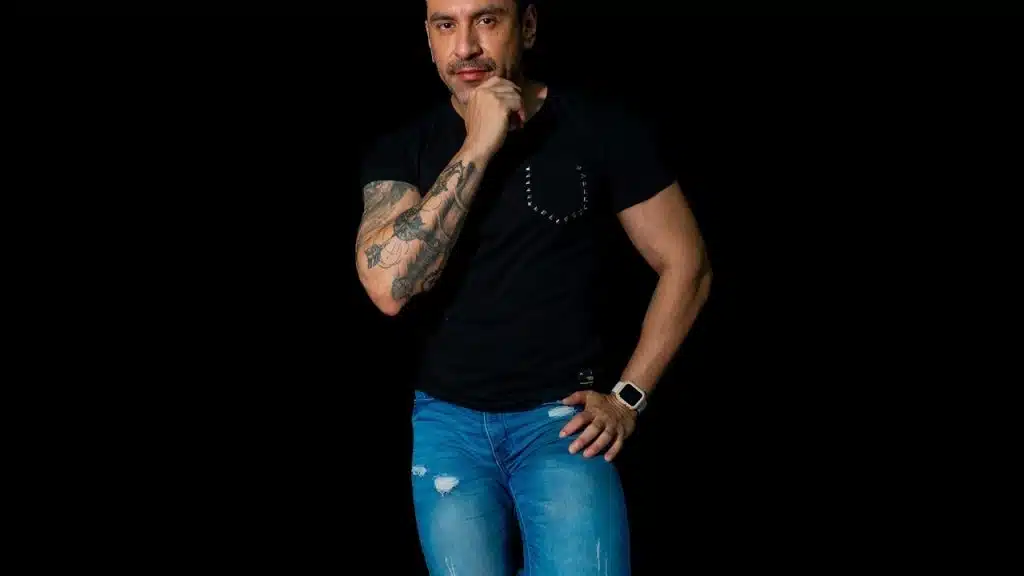 A portrait of a stylish man in blue jeans on a black background.
