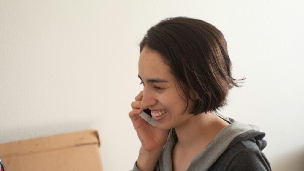 A smiling woman is talking on the phone.