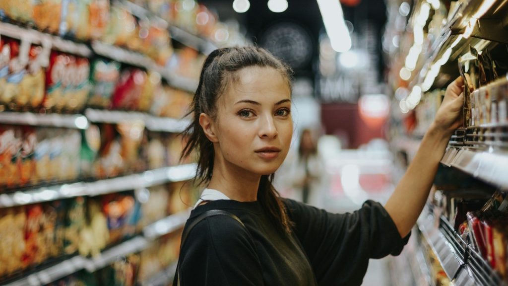 A woman shopping in a grocery store and looking at the camera.