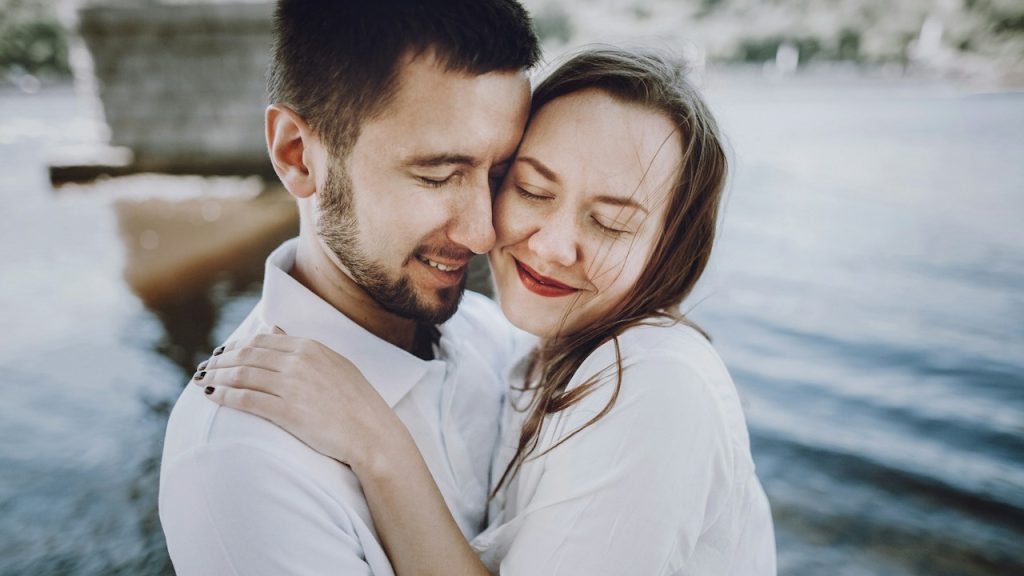 A couple in love, hugging on the beach in a summer city.