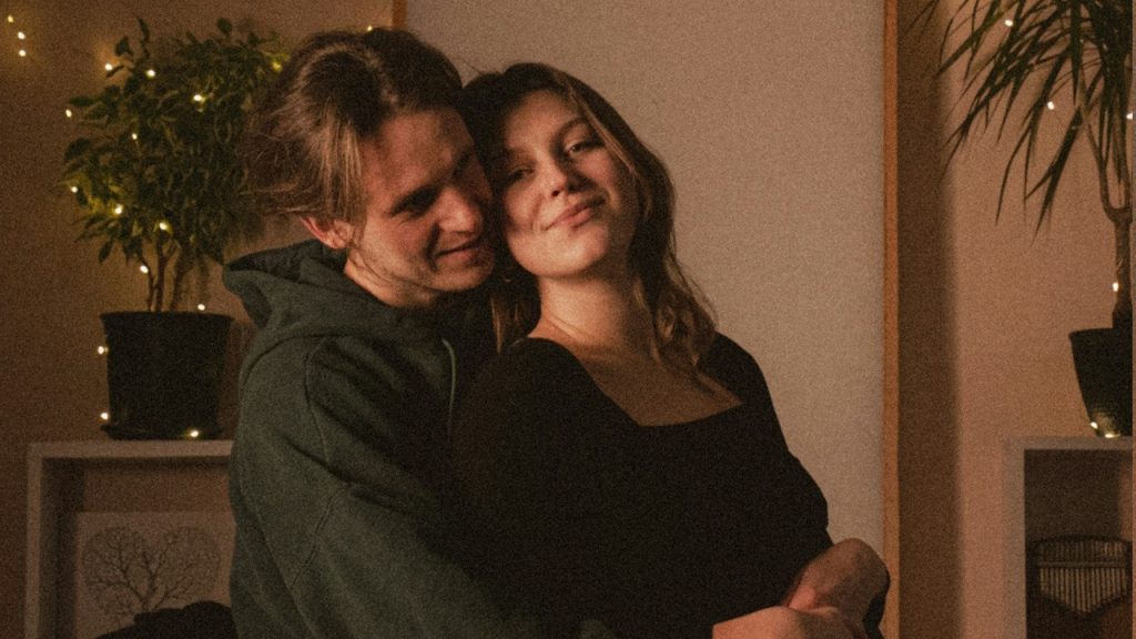 Young couple embracing indoors with string lights.