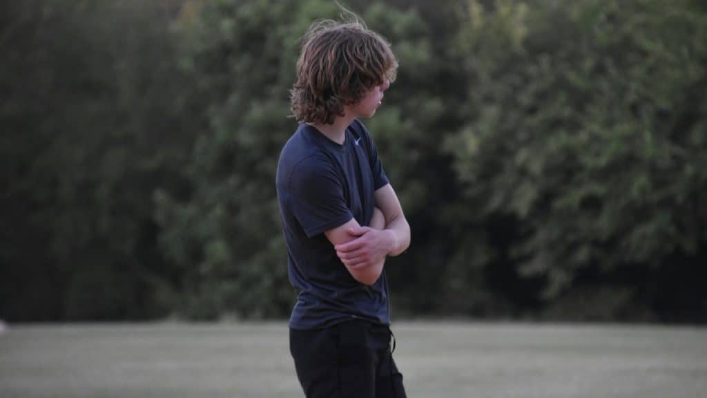 A man standing in front of a body of water with his arms crossed.